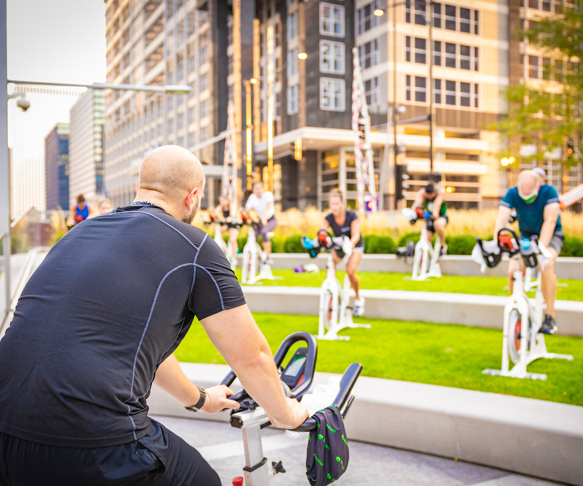 An instructor leads an outdoor cycling class
