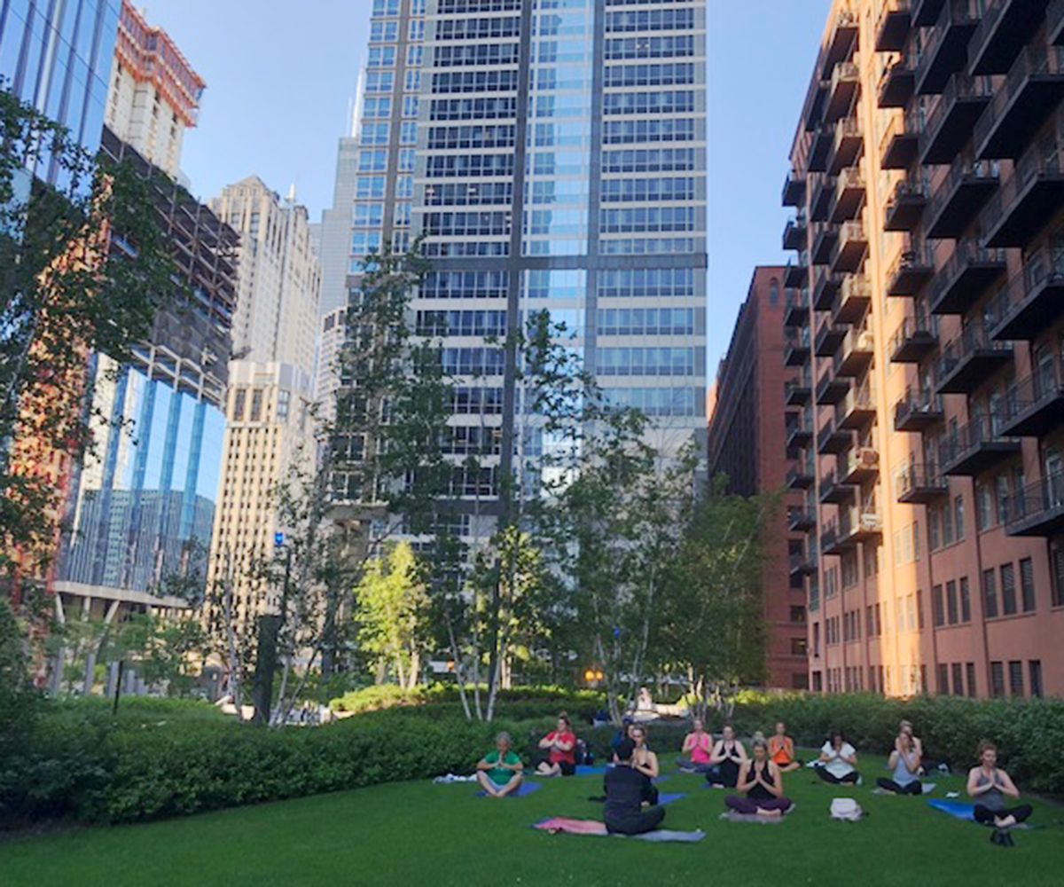 A yoga class takes place in the grassy park area of 150 Riverside