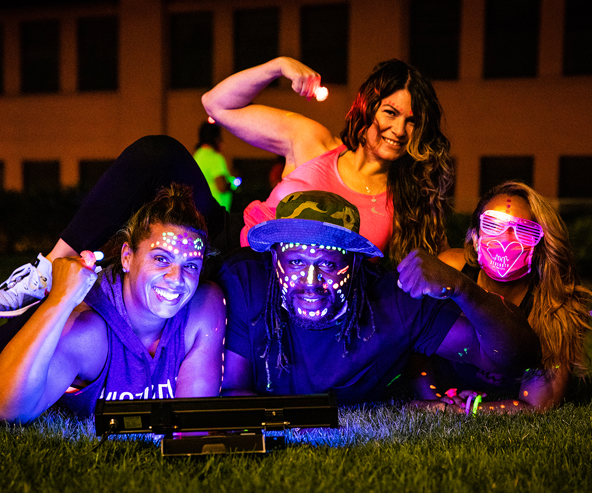 Friends with glow in the dark facepaint pose laying in the grass together